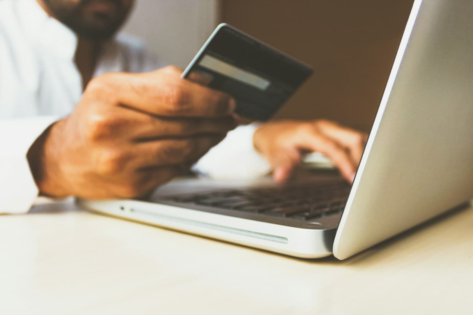 Person holding a bank card while typing on a laptop
