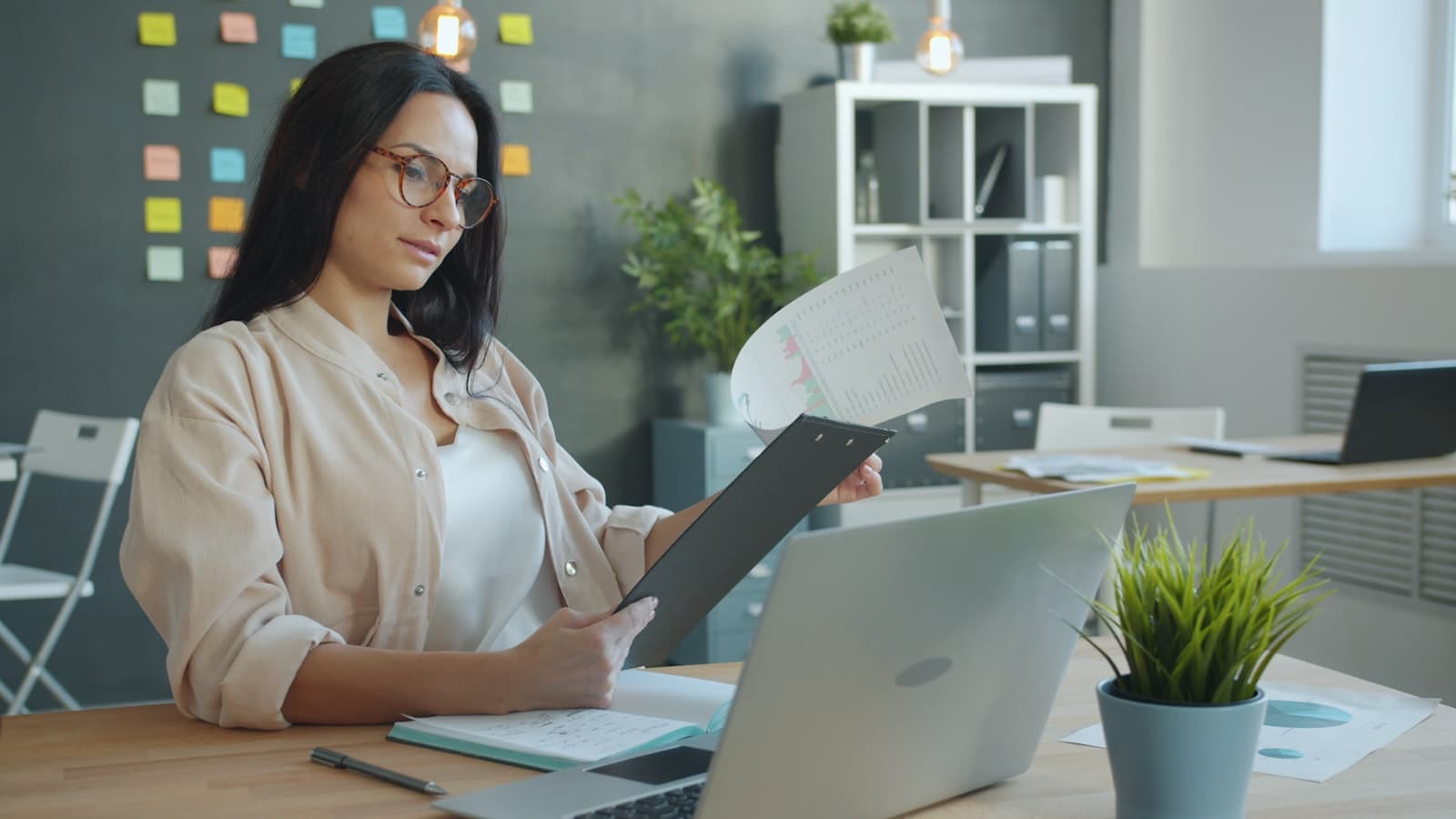 A professional carefully reading a printed report at an office desk
