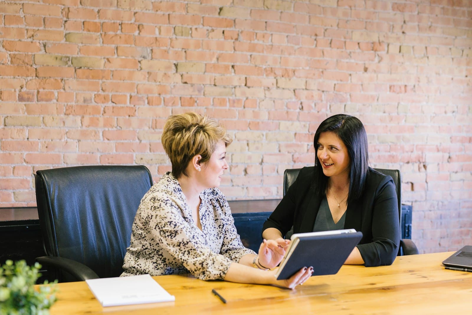 Two people talking across a table in a bright office