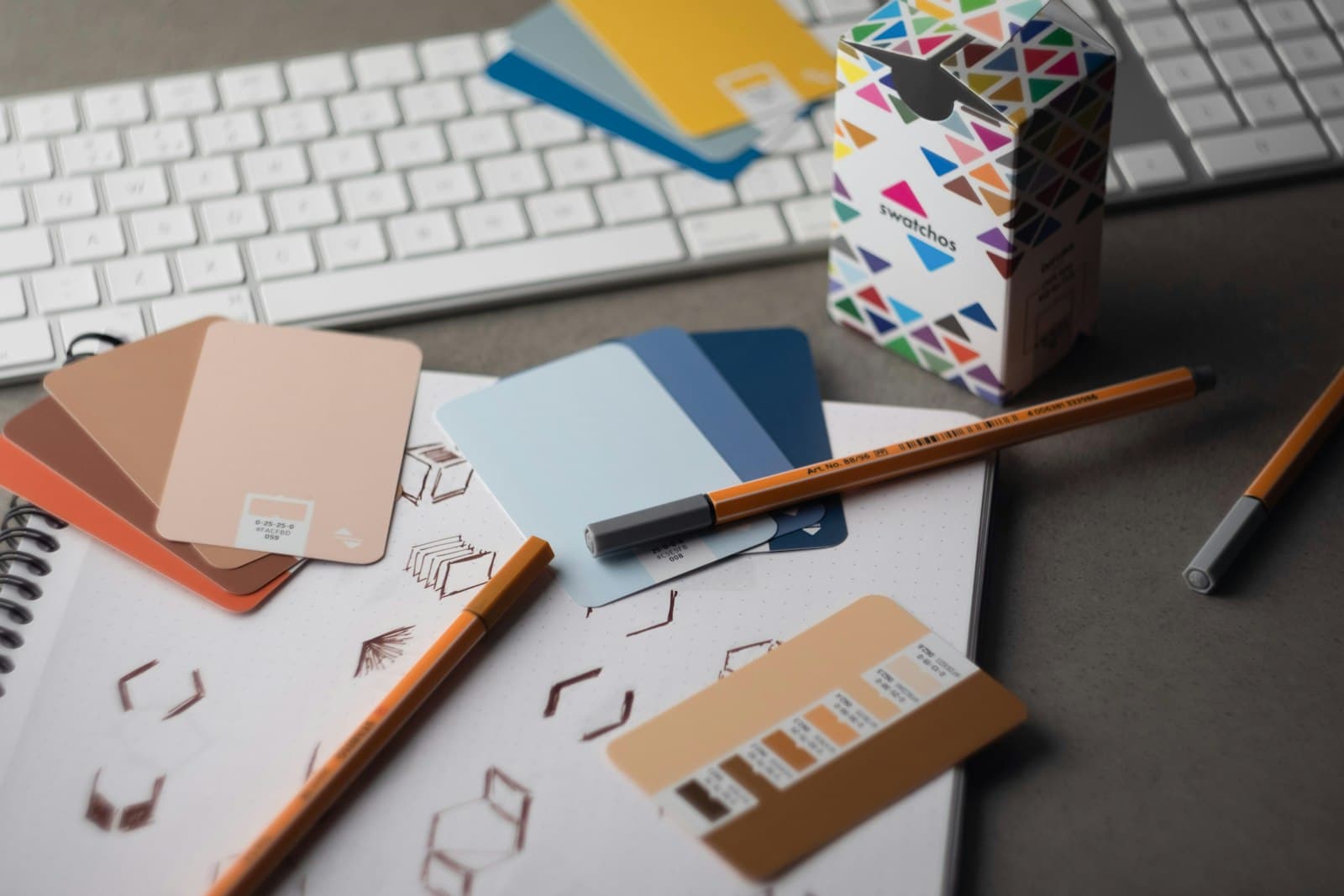 Color swatch cards and pens spread across a designer's desk