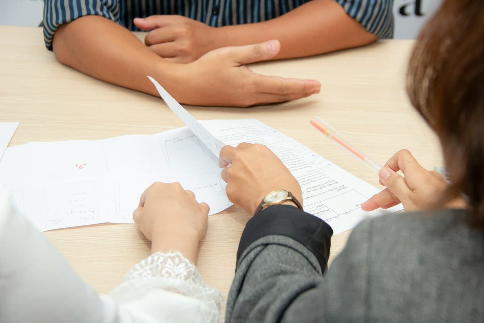Two people at a table comparing and pointing at printed documents