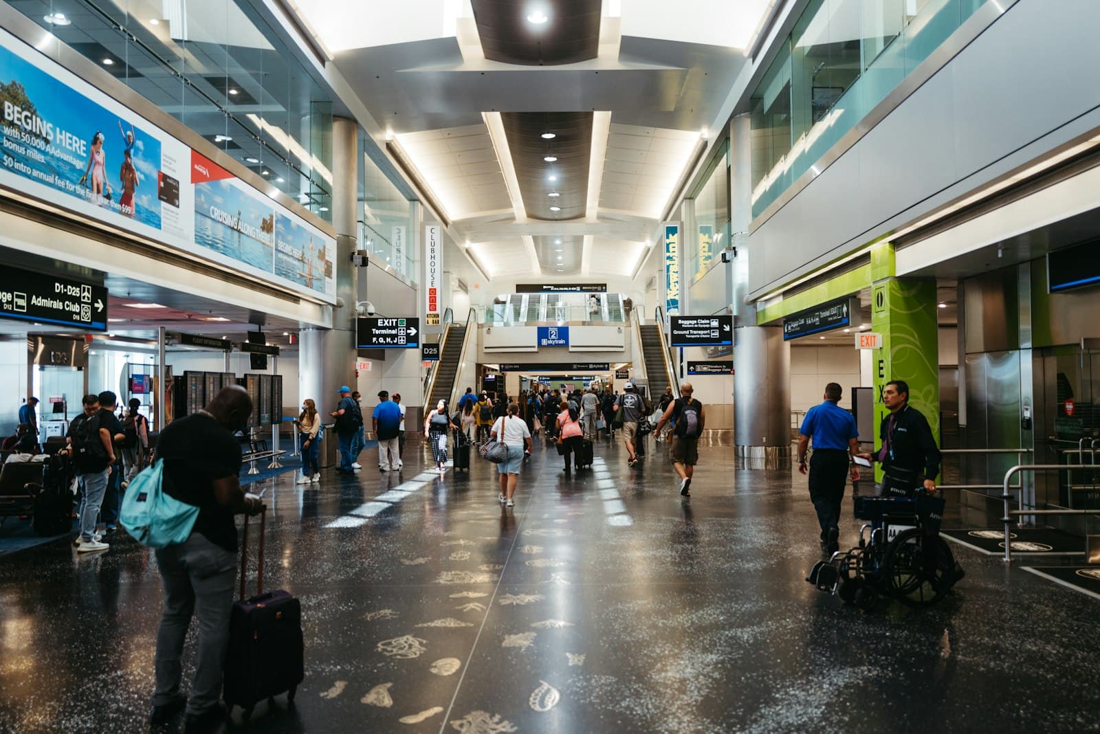 Travelers with luggage walking through a busy U.S. airport terminal