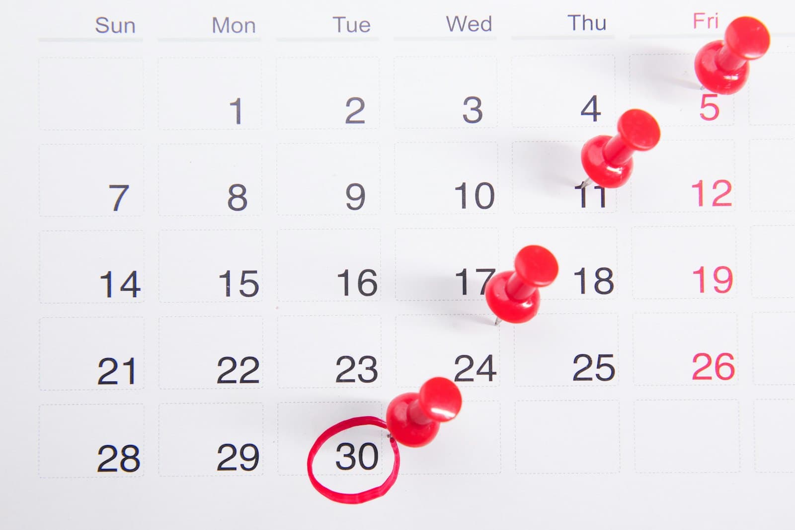 A calendar with red push pins marking a countdown to the 30th, which is circled in red