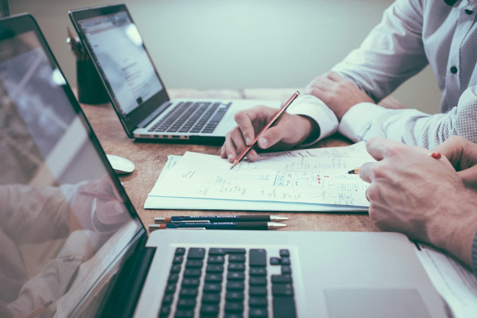 Two people reviewing and annotating a stack of documents at a desk