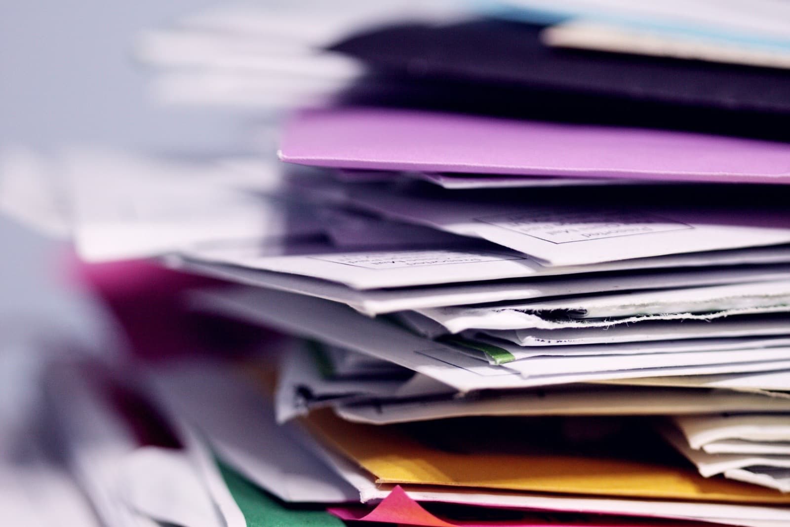 A tall stack of unopened mail and envelopes waiting to be sorted